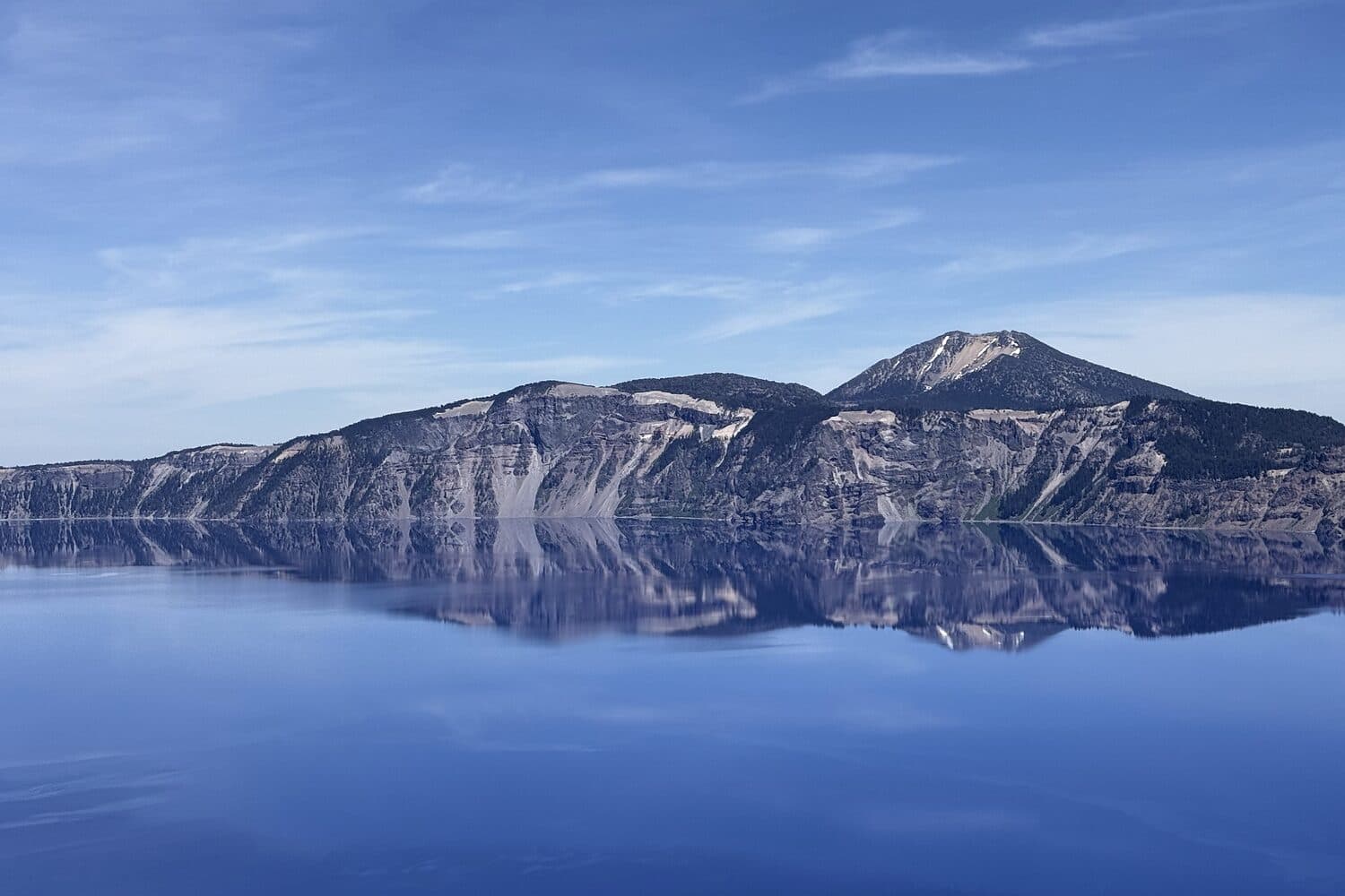 Wizard Island standing in the still blue of Crater Lake under a clear morning, Oregon