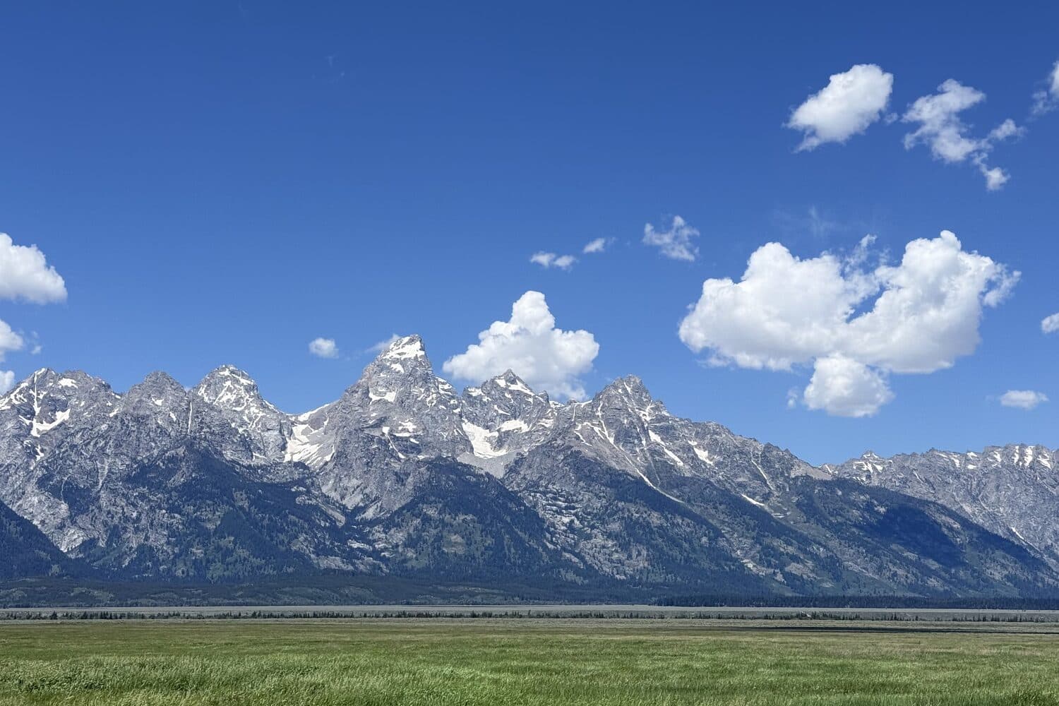 The Teton range standing over the sage flats under high summer cloud, Wyoming