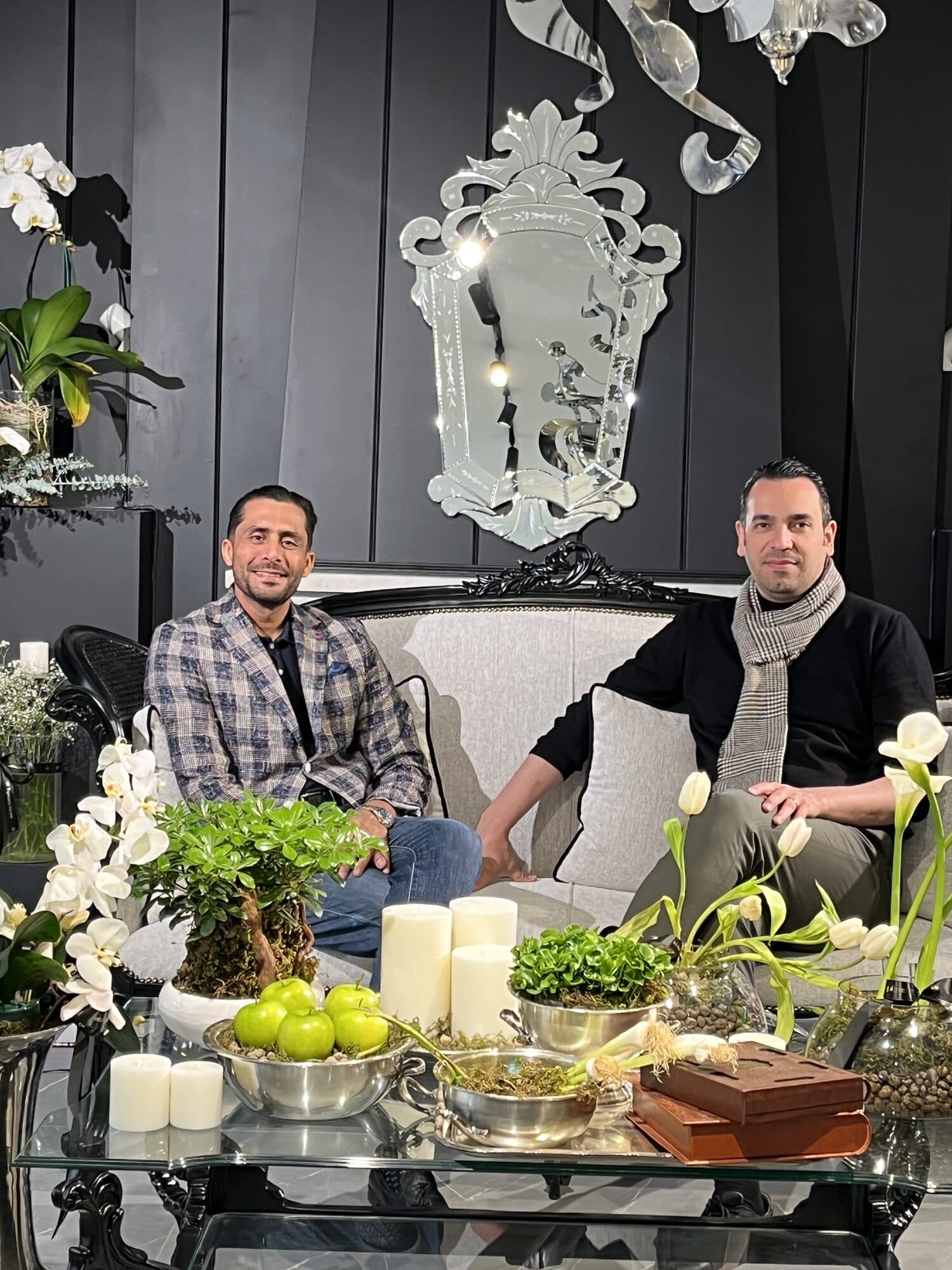 Two members talking on a sofa in the same lounge, tulips and a bowl of fruit on the table in front of them
