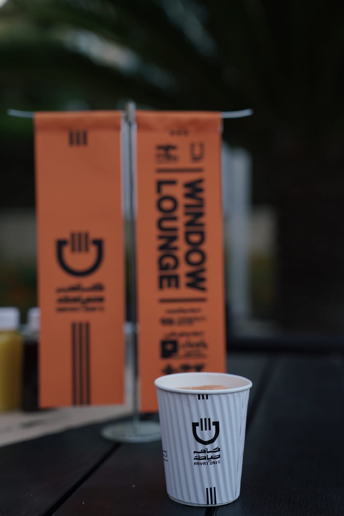 A WINDOW LOUNGE banner in the club's orange, a paper cup on the counter in front of it