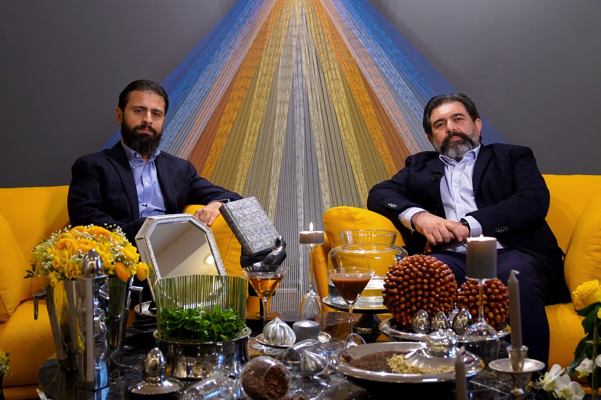دو مهمان کنار هم روی مبل، پشت سفره‌ی هفت‌سین، در یکی از سی شب پیاپی.