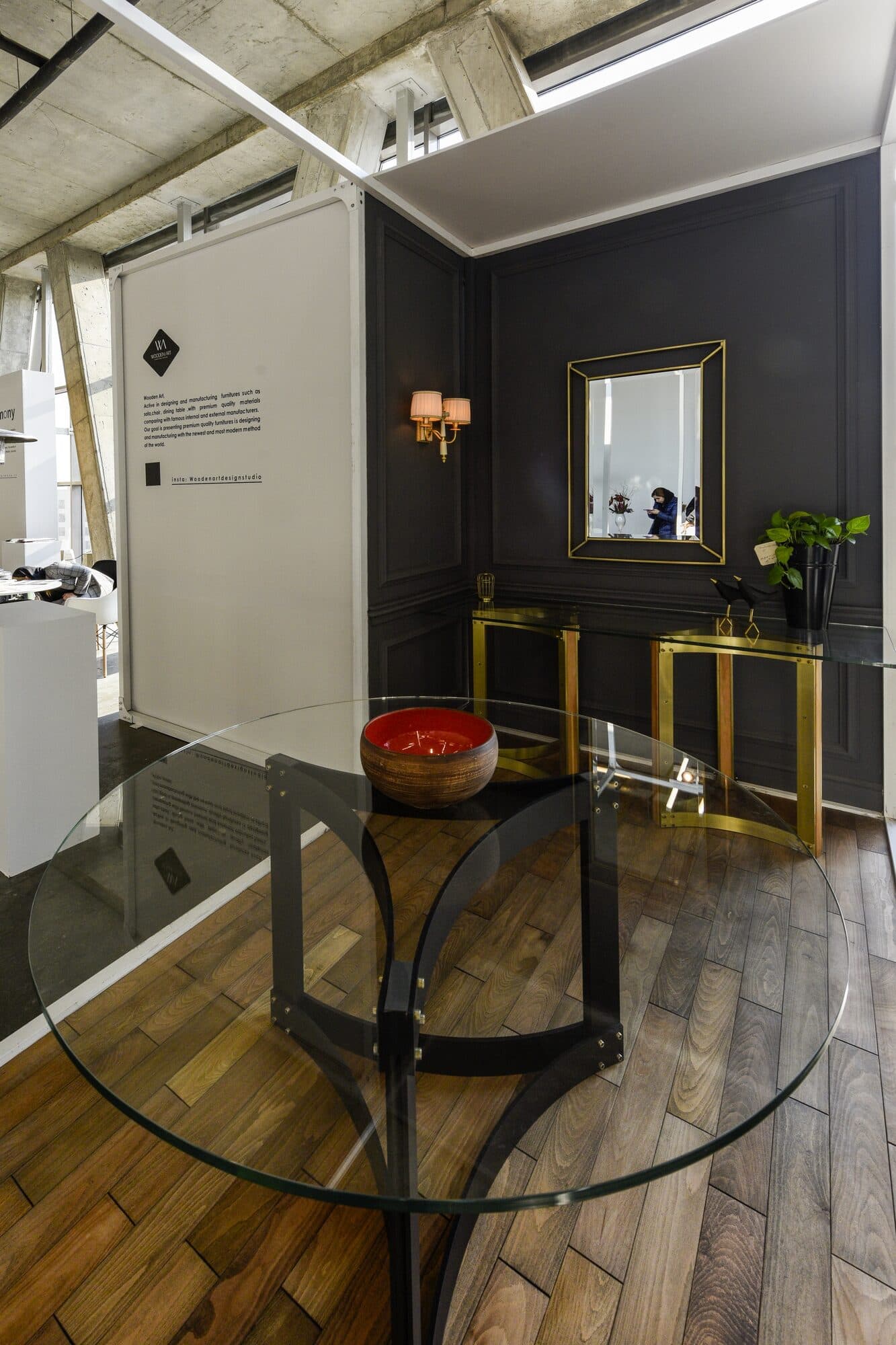 A panelled room in charcoal and brass — a glass table, a gilt console and a mirror