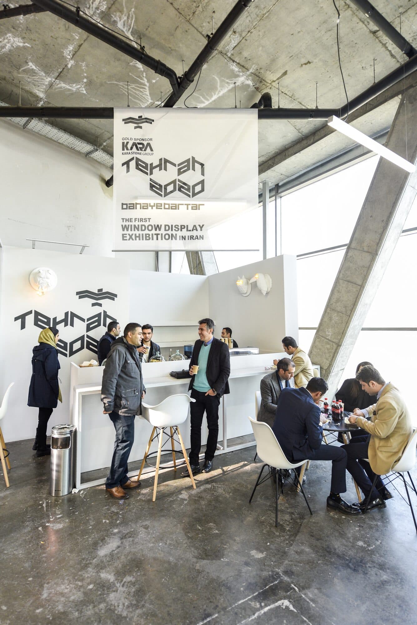 High tables under the hall's steel trusses, groups standing in conversation