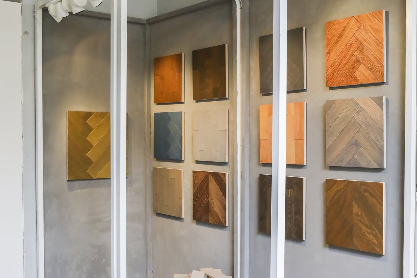 A room of parquet panels hung as samples on a raw concrete wall