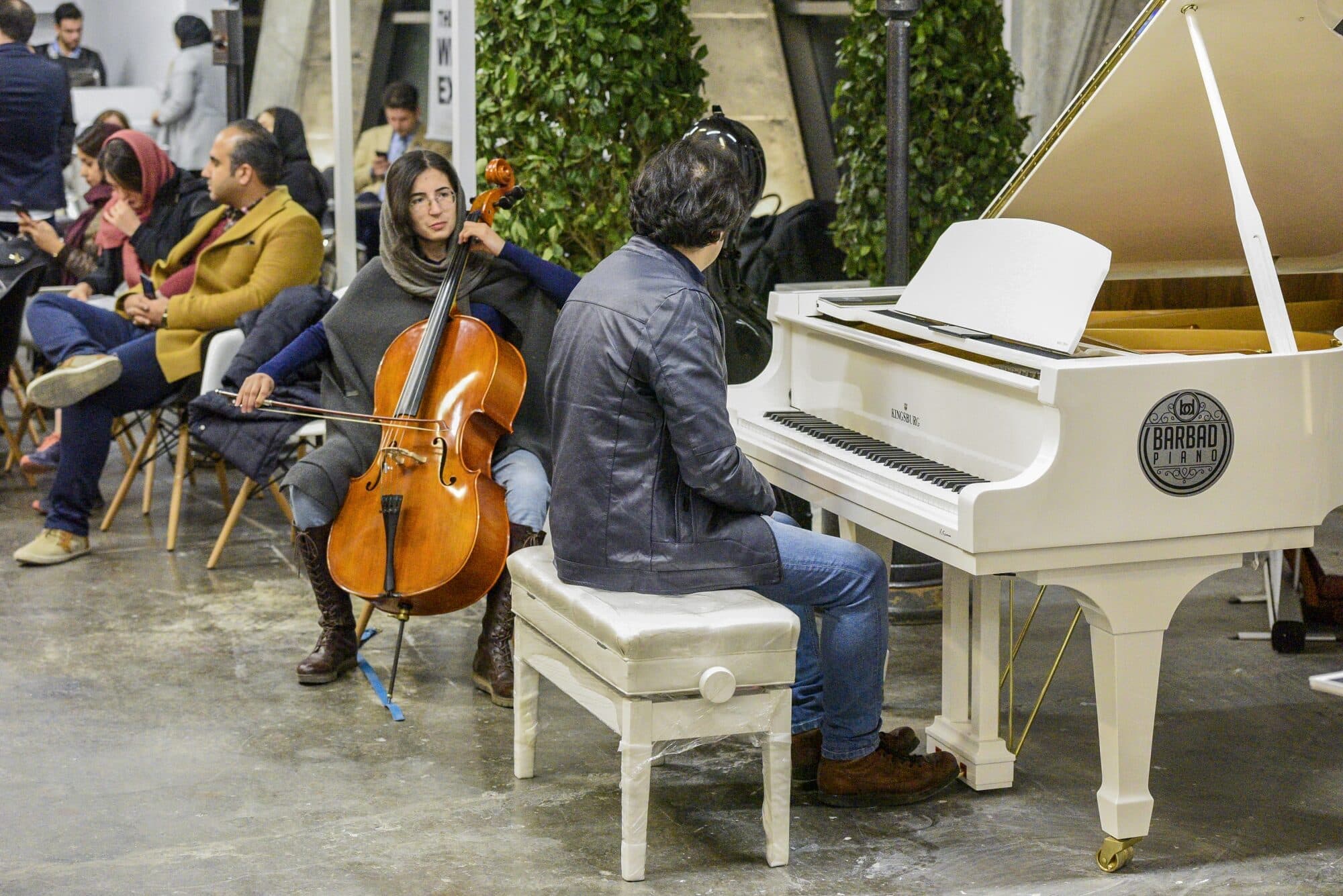 A string quartet and a grand piano playing at the green wall, visitors listening from the seating