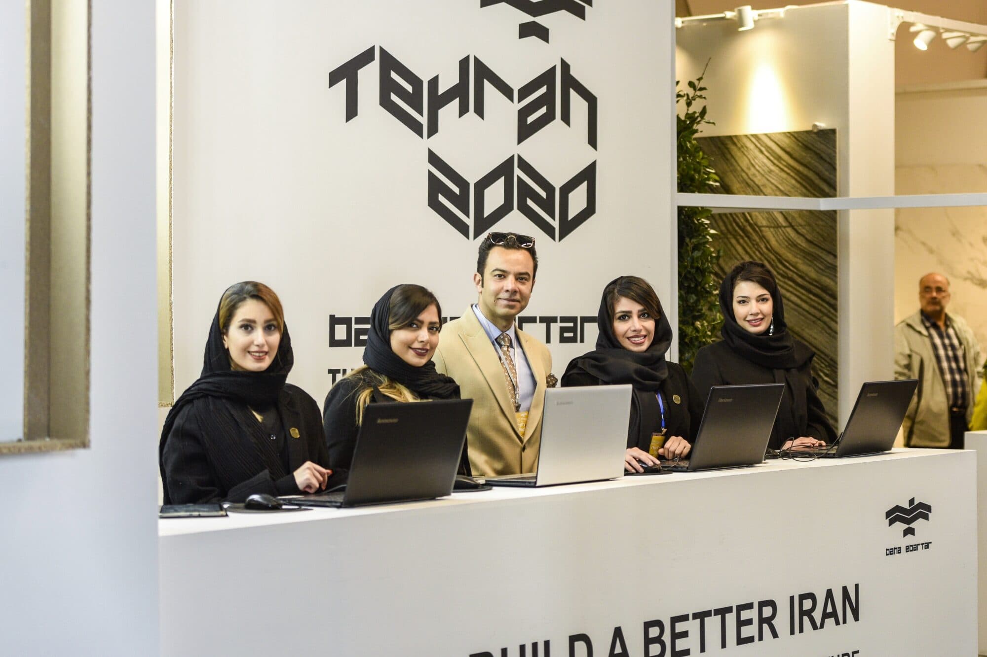 The reception desk with the team behind it, under the banayebartar wordmark and the line WE CAN BUILD A BETTER IRAN