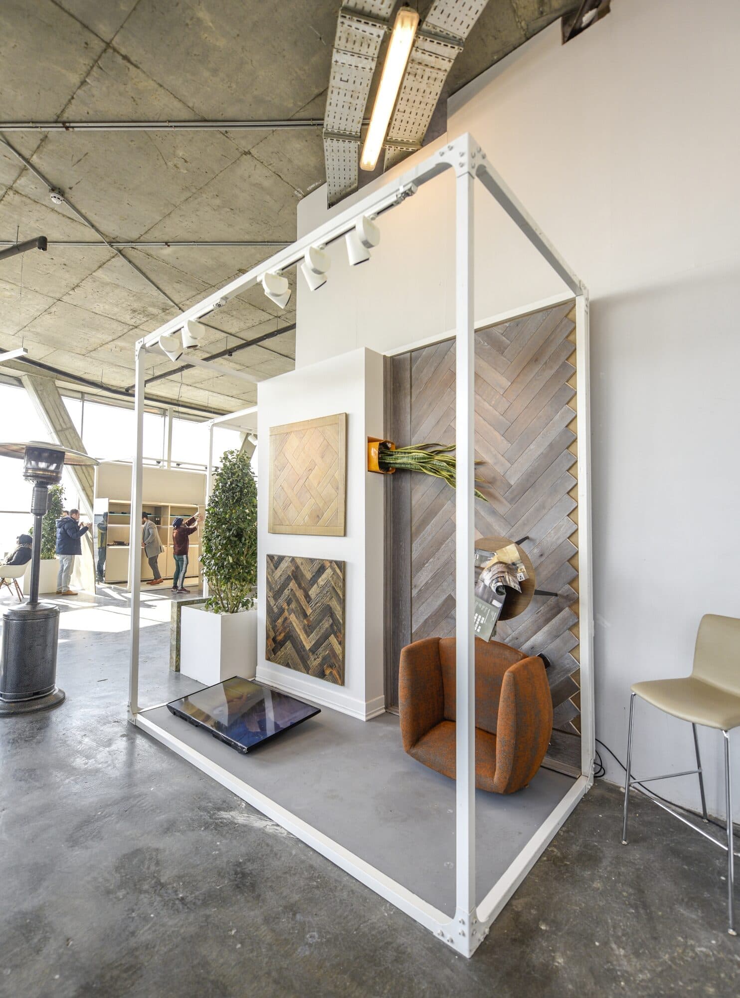 A white frame cabin with veneer samples on its walls and one armchair inside it