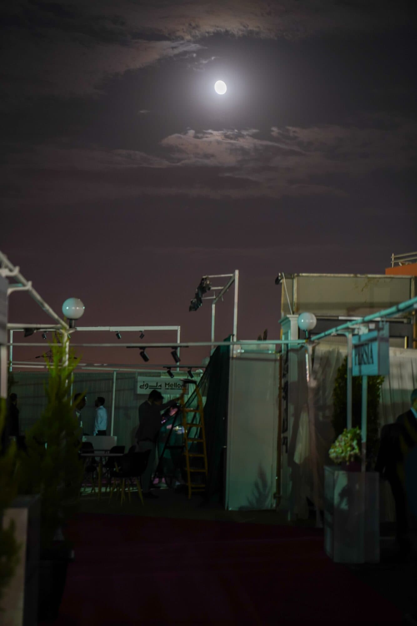 The deck under a full moon, the stands lit and the last visitors between them