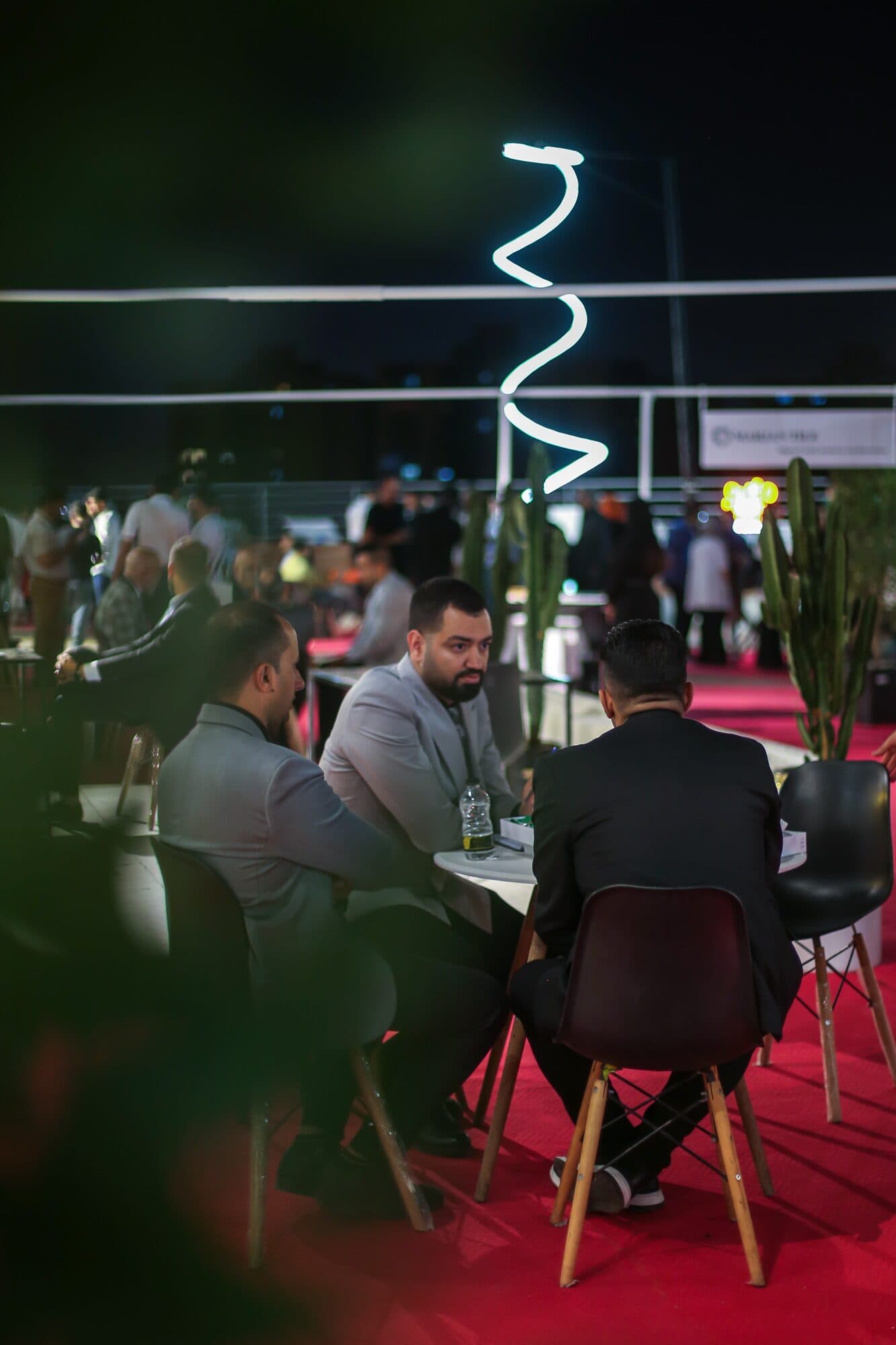 Tables on the deck after dark, a neon line drawn above them and the route glowing red