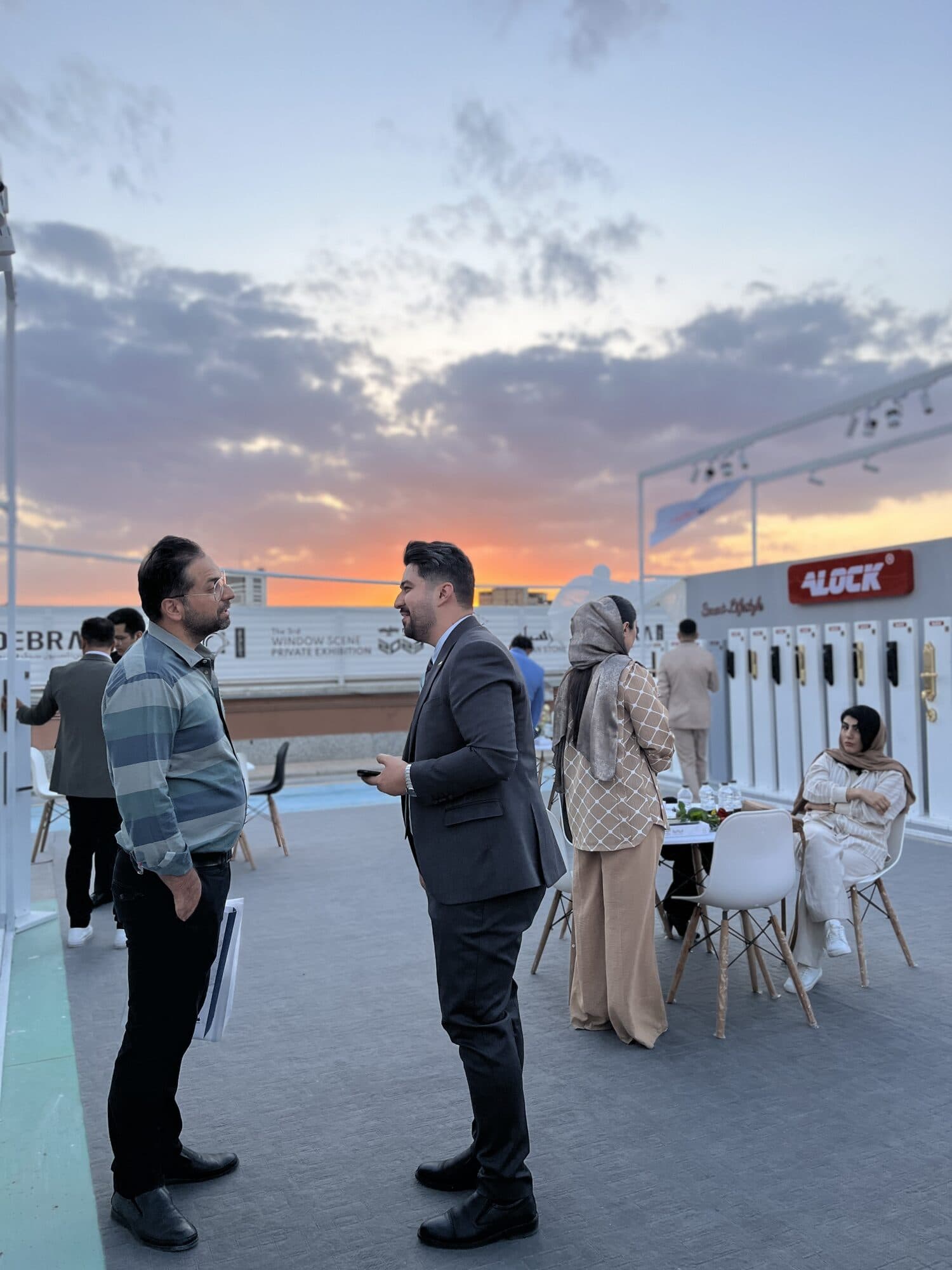 Two visitors talking on the deck at sunset, the stands and the skyline behind them