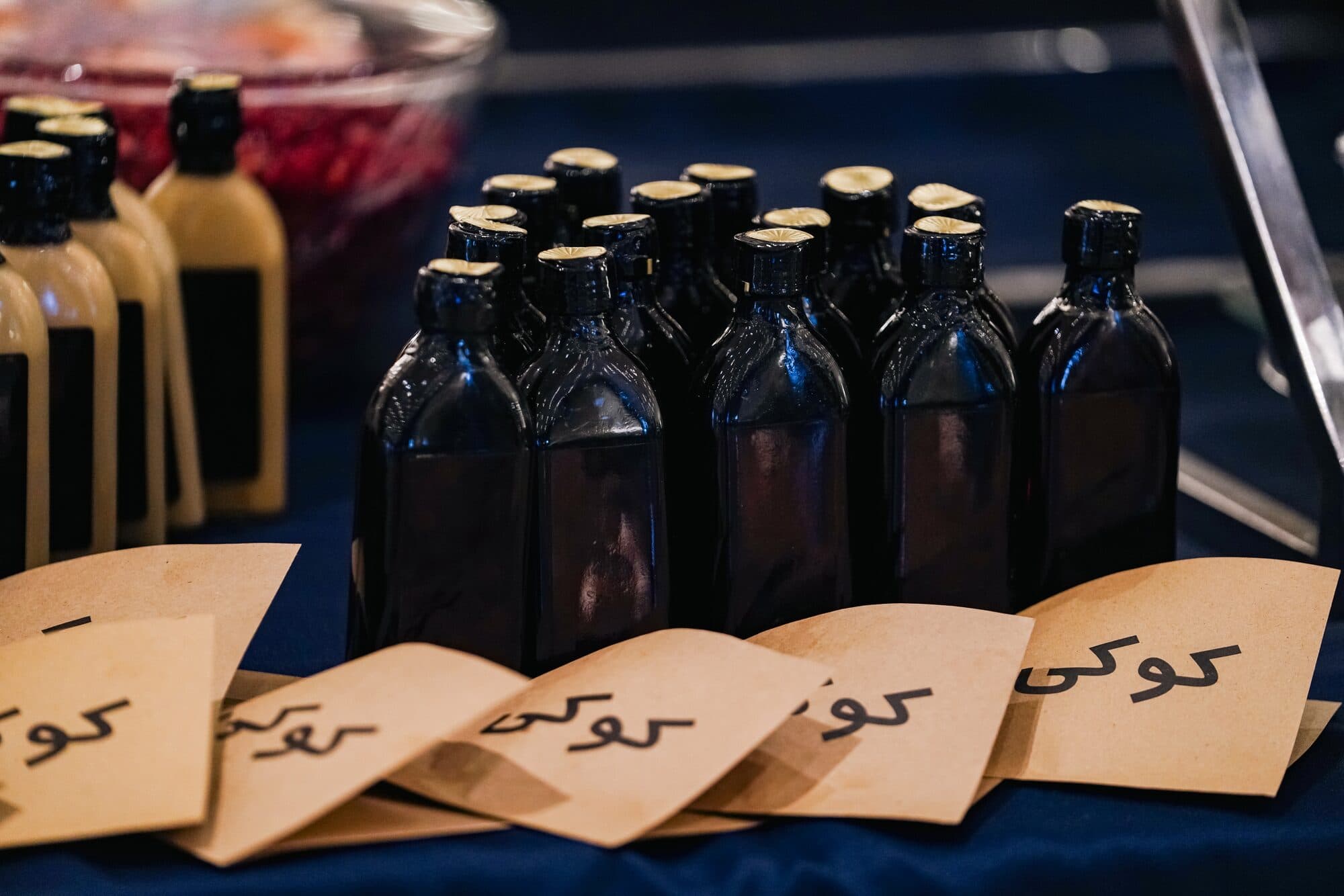 Bottles set out with hand-lettered kraft cards on the reception table