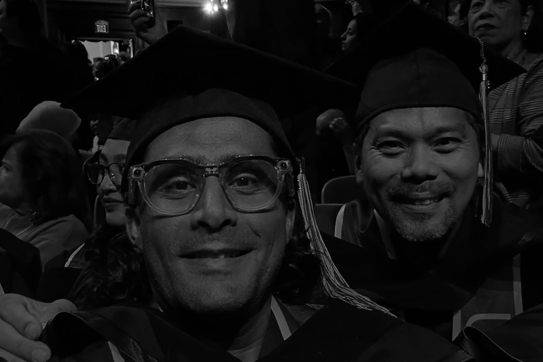 Ehsan Kaykhah and a classmate in the audience in cap and gown, waiting for the ceremony to begin