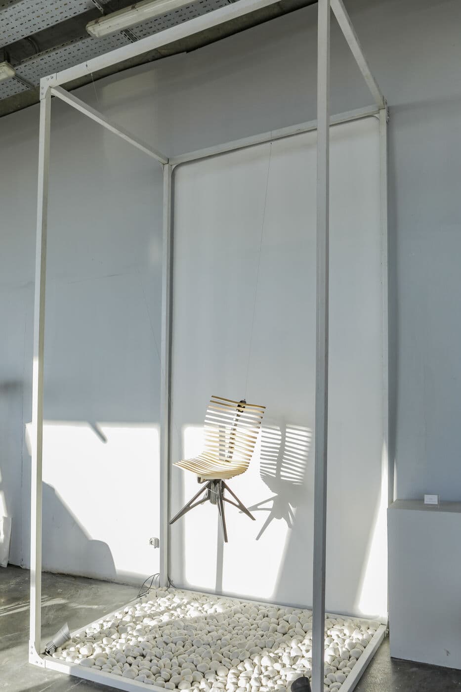 A single chair inside an empty white frame on a bed of white pebbles — WINDOW DISPLAY, Tehran 2020