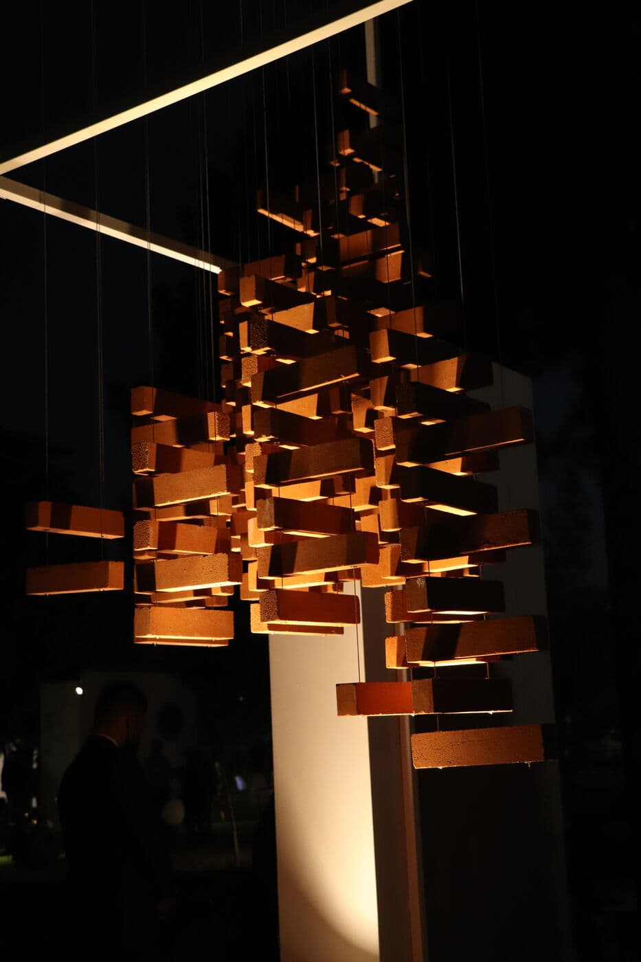 A suspended installation of copper blades lit against the night — WINDOW GARDEN, Mashhad 2021