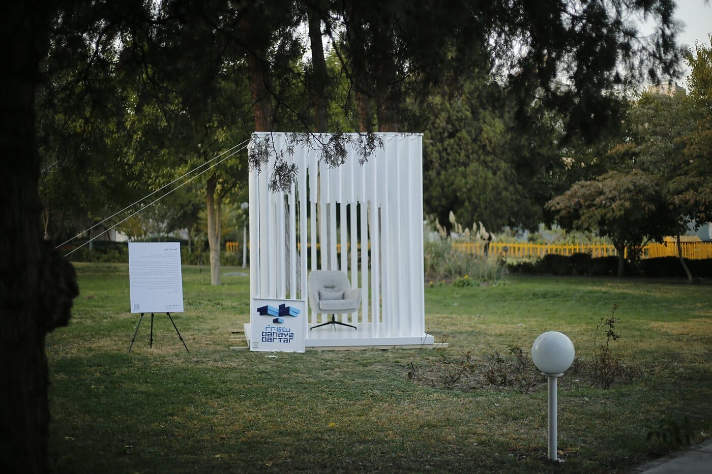 A white slatted pavilion standing alone on the lawn between the trees — WINDOW GARDEN, Mashhad 2021