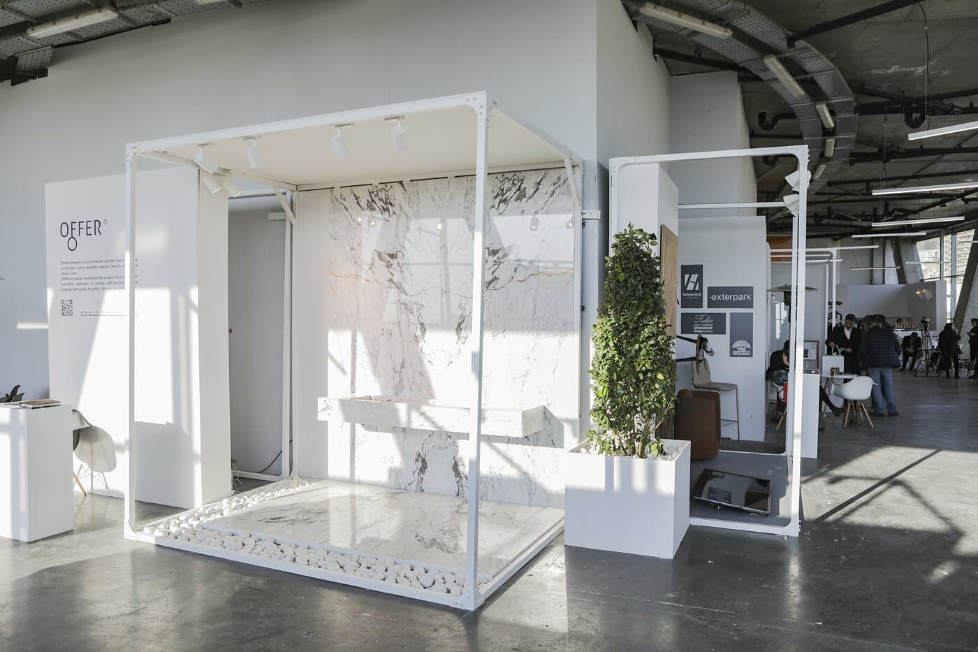 The hall of white frames at WINDOW DISPLAY, each setting an identical structure holding a different brand, Tehran